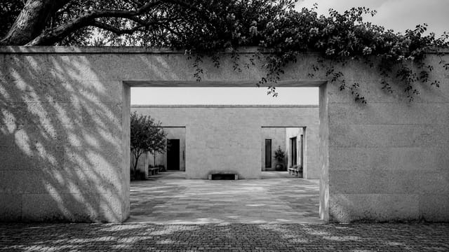Tor in monochromer Steinmauer mit Blick in einen Innenhof
